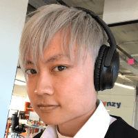 A headshot of an asian looking person wearing headphones facing the camera